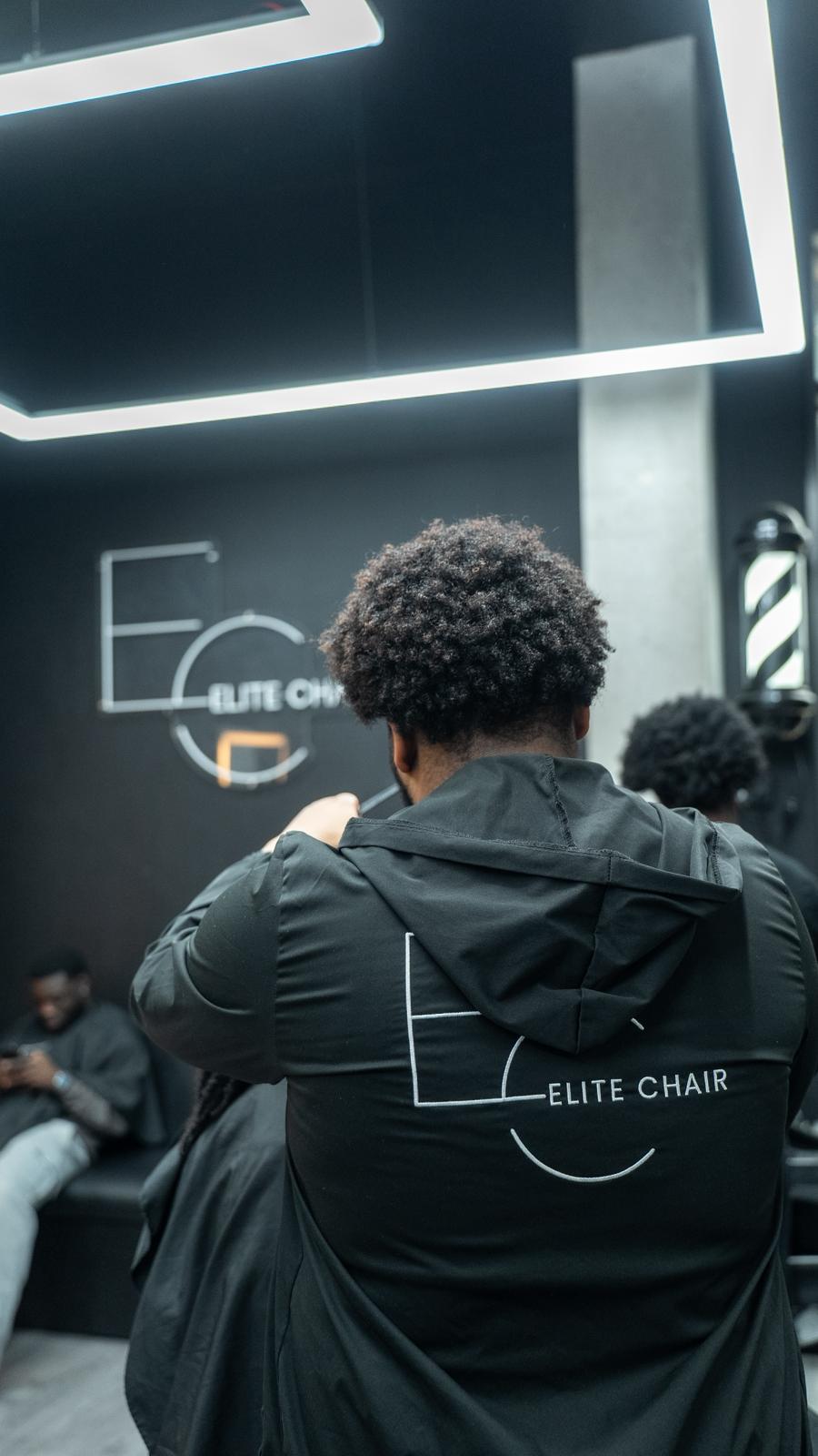 Elite Chair Barber branded apron during a haircut service in Canning Town