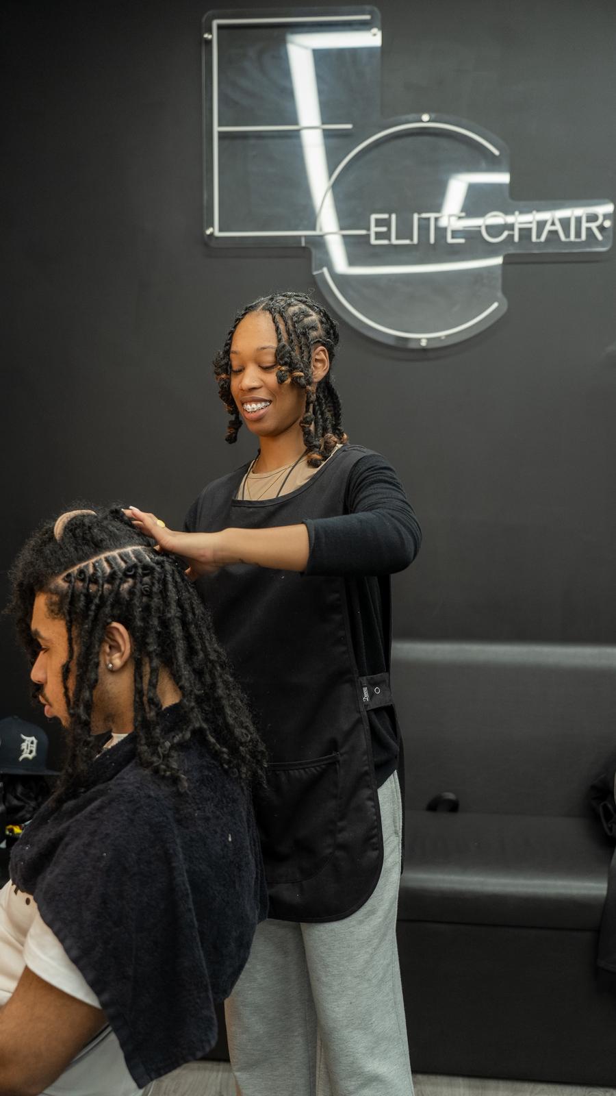 Elite Chair hairdresser smiling while working on locks