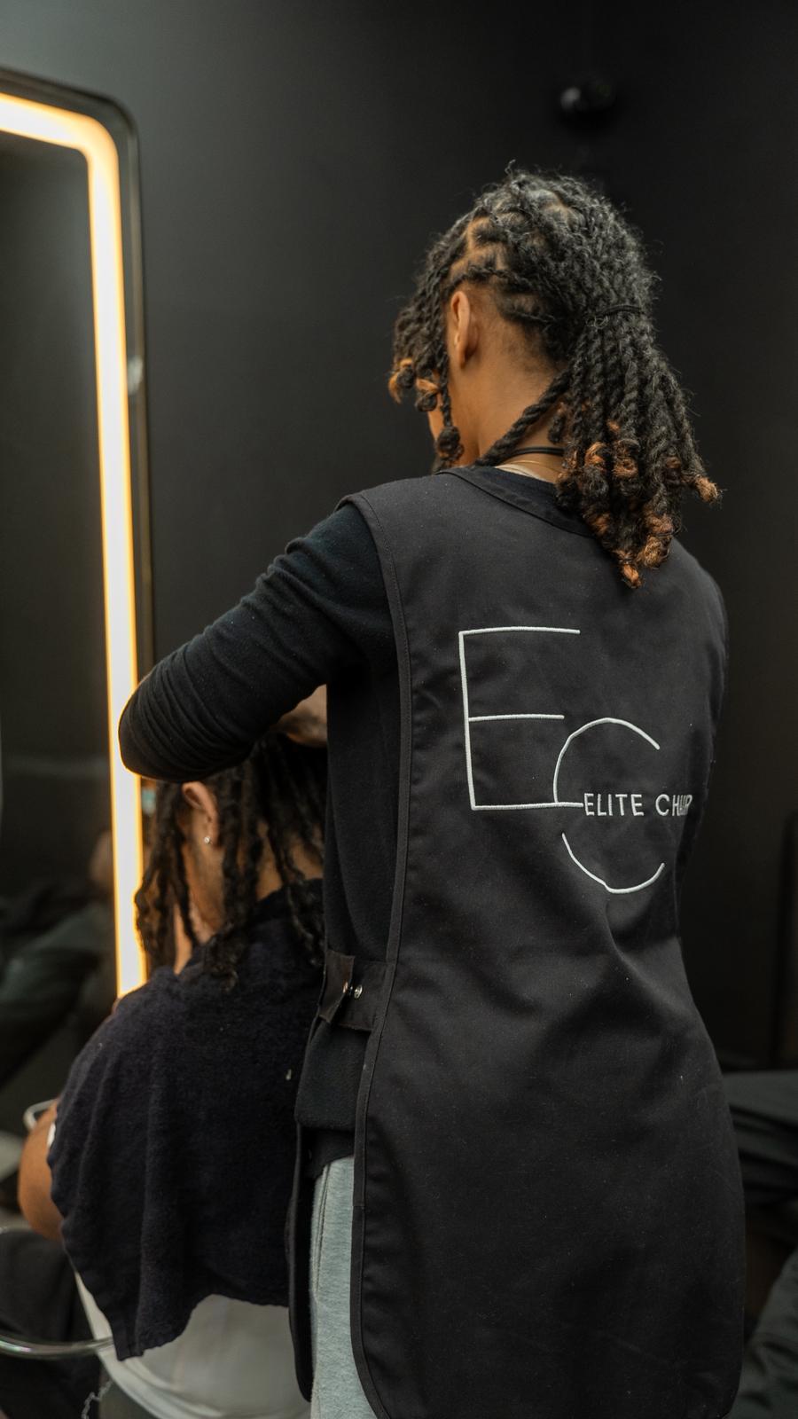 Elite Chair branded apron during a professional hair service